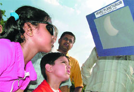 Students watch partial solar eclipse from Nehru Planetarium in New Delhi on Friday.