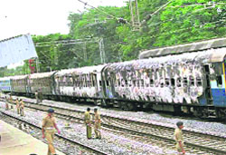 Police personnel near the charred coaches of the Gautami Express that caught fire in Waranagal district of Andhra Pradesh