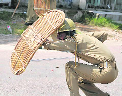A policeman on Saturday ducks behind his shield to protect himself from protesters during the ongoing agitation in Jammu against the land revocation order. 
