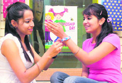 A girl ties a band on the wrist of a friend on Friendship Day in Chandigarh on Sunday. 