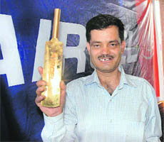 Ishwar Chand Thakur, lucky winner of Aircel cricket contest, with half a kg gold bat in Shimla on Monday.