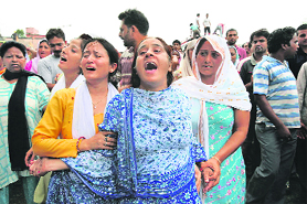 Relatives of Sanjeev Singh, a protester who was killed in a clash with the police during a demonstration on Monday, mourn during his funeral in Samba.