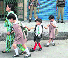 A Kashmiri woman with her children walk in front of closed shops during the second day of strike in Srinagar on Tuesday.