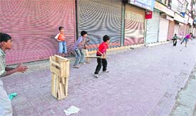 Strike gives children some cricket time in front of closed shops in Srinagar on Wednesday