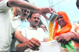 Members of a welfare committee distribute rice and other food items among the poor in Jammu on Thursday