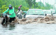 Vehicles make their way through a waterlogged road near Rajghat