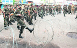 Troops block a road with a barbed wire during curfew in Jammu