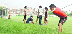 A hockey player cuts grass at a school in Ludhiana.