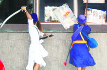 Sikh activists brandish swords and sticks outside a cinema hall screening the film, Singh is Kinng, in Amritsar on Friday.