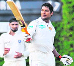 Kumar Sangakkara (R) raises his bat as he is applauded by the crowd after completing his century as Harbhajan Singh looks on during the second day of the third Test between India and Sri Lanka at The P. Saravanamuttu Stadium in Colombo