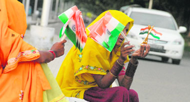 Women at a light point in Chandigarh sell national flags as Independence Day approaches