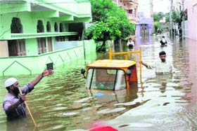 People wade through a rain-flooded street in Hyderabad