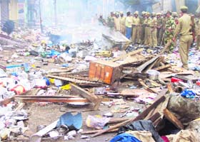 Policemen survey the wreckage after a mob damaged shops in Kishtwar