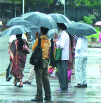 People armed with umbrellas stand at a bus stop in New Delhi on Wednesday.