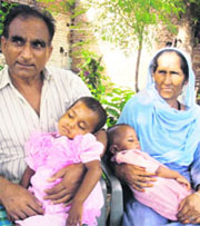 Two siblings of a Hindu family fast asleep in the laps of Muslim couple Ahmed Din Bhat and Salima Begum ouside their house in Gangyal.