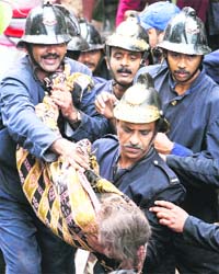 Firemen carry the body of a victim from the debris of a building that collapsed in Mumbai