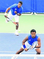 Mahesh Bhupathi (L) serves as Leander Paes prepares to play during the men's doubles match in Beijing on Wednesday.