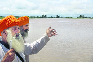 Two villagers point to a flooded link road in Maste Ke village. 