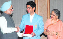 Abhinav Bindra (C) displays his gold medal as Prime Minister Manmohan Singh (L) and his wife Gursharan Kaur look on during their meeting in New Delhi