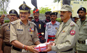 BSF DIG V.K. Sharma giving a pack of sweets to Pakistan Rangers at the Sadiqi joint check-post in Fazilka sector on Friday.