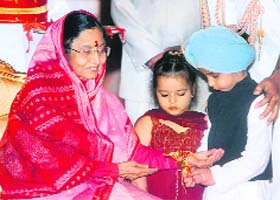 A little boy ties a rakhi to President Pratibha Patil on the occasion of Raksha Bandhan at the Rashtrapati Bhavan in New Delhi