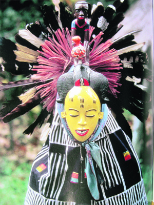 A performer in a Flali masquerade, wearing a painted mask. Guro, the Ivory Coast. Photograph by Lorenz Homberger, 1983.