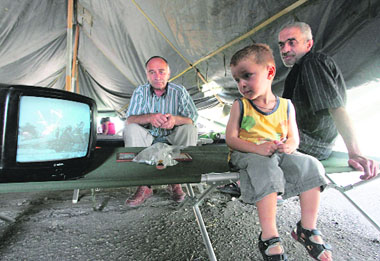 Georgian refugees from South Ossetia watch TV showing local conflict-related news at a refugees camp outside Tbilisi on Saturday.