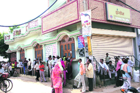 People await their turn to get LPG cylinders refilled from a distributor in Rohtak on Sunday.