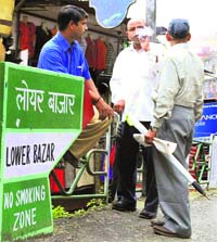 BAN GOES UP IN SMOKE: Not caring two hoots for the ban on smoking, a man puffs a cigarette standing beside a board proclaiming the area to be a no-smoking zone, in Lower Bazar, Shimla