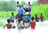 Children play on a cart at the flooded Yamuna Pusta area in East Delhi on Tuesday.(Right) People shift with their household items near Shastri Park in New Delhi.