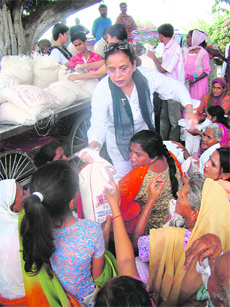 Residents of Gandhi Nagar distribute free ration among the poor in Bag-e-Bahu Locality of Jammu on Thursday.