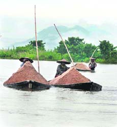 People carry sand on country boats from the Kulsi river in Chaygaon on the outskirts of Guwahati