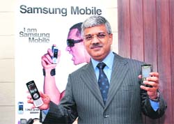 Samsung Indias country head for telecommunications business, Sunil Dutt, poses with latest range of mobile phones at Samsungs Noida factory on Wednesday.