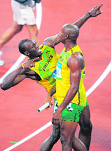Jamaica's Usain Bolt (L) celebrates with teammate Asafa Powell after they won the men's 4100m relay final timing a new world record of 37.10 sec.
