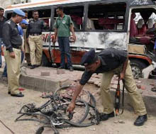 Pakistani police officers examine a bus and wreckage of a bicycle after a bomb explosion in Karachi on Saturday. A bomb rigged to a bicycle went off near a vehicle carrying a senior police investigator Raja Umar Khatab, who has played a key role in arresting many militants in recent years.