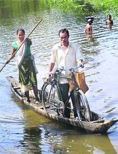 People use a country-made boat to cross a flooded area near Guwahati