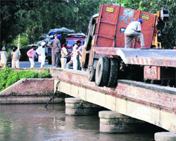A truck perched precariously on a bridge near Sahnewal in Ludhiana on Monday.