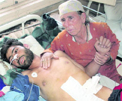 An old woman attends to her son injured in police firing at Hajan Bandipora in a Srinagar hospital 