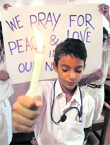 A student holds a candle during a prayer ceremony held for the victims of last months bomb blast, at a school in Ahmedabad