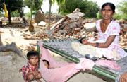 A boy rocks his brother to sleep while his mother cuddles another child even as their house was being demolished.