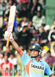 Suresh Raina raises his bat to the crowd after scoring a half-century