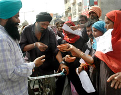 Residents of Dhobiana Basti dressed in black attire beg in a symbolic show of protest against the demolition of their houses by PUDA.