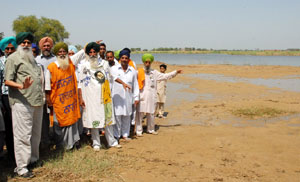 Farmers show the waterlogged area to their leader Ajmer Singh Lakhowal at the Mahapanchayat, held at Lundewala village near Gidderbaha in Muktsar district, on Friday. 