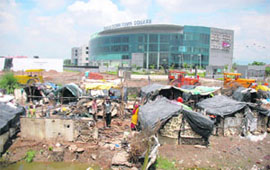An illegal slum alongside a mall depict the growing disparity in society.