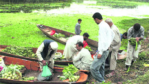 People buy vegetables on the banks of the Dal Lake during curfew relaxation in Srinagar on Sunday.