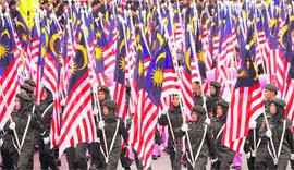 Participants march through with Malaysian flags during a parade at the Merdeka Square in downtown Kuala Lumpur on Sunday. Malaysia celebrated 51 years of independence on Sunday, wracked by economic woes and political uncertainty over fears that a resurgent opposition could topple a government that has ruled since 1957 when British colonial rule ended