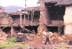A resident walks past a collapsed house after an earthquake hit Lixi town in Huili County, Sichuan province, on Sunday. 