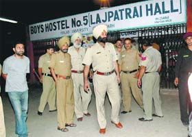 Police officials emerge from boys hostel No 5 at Panjab University in Chandigarh