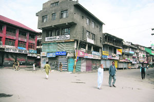 People walk past closed shops during a strike call given by the coordination committee in Srinagar on Saturday.