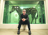 British artist Damien Hirst poses for photographs in front of his work entitled 'The Incredible Journey' during a photocall at Sotheby's art gallery and auction house in central London